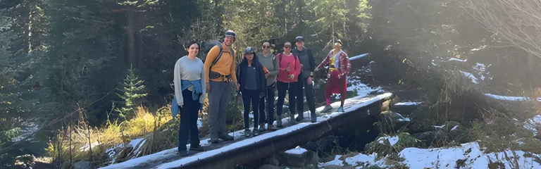 seven people posing on a bridge in the forest