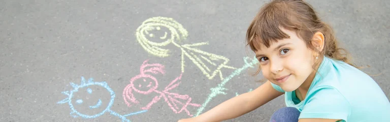 kid drawing on the street with colored chalk